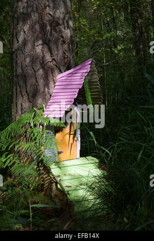 Piccola porta d'ingresso per una casa di fata con tetto di portico rosa e porta arancione nel Woods, Inghilterra, Regno Unito. Foto Stock