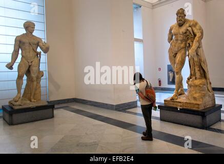 Un visitatore lookig alla statua di Ercole Farnese, esposta al Museo Archeologico Nazionale di Napoli Foto Stock