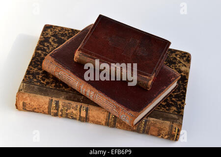 Vecchia tre libri con rosso e marrone a copertina rigida e lettere dorate appoggiata su uno sfondo bianco Foto Stock