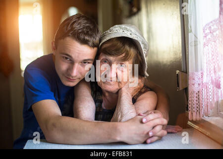 Nipote abbracciando la nonna in posa per un ritratto. Foto Stock