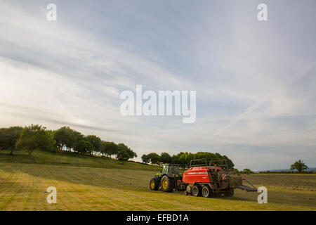 Il trattore e la pressatura di fieno pressatura di fieno in campo, Oxfordshire, Inghilterra Foto Stock