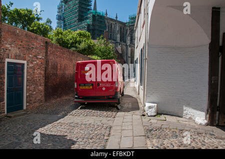 Rosso brillante Post Office van parcheggiato sulla storica, strette e acciottolate Capitolo House Street, York con il Ministro al di là - North Yorkshire, Inghilterra, Regno Unito. Foto Stock