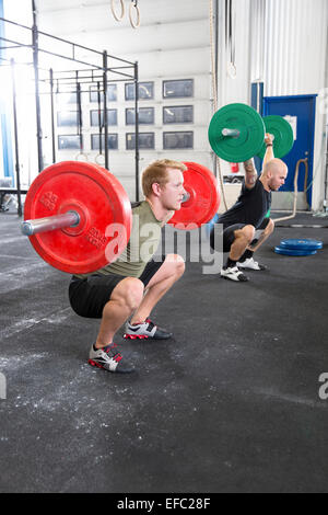 I treni del team squats in palestra per il fitness center Foto Stock