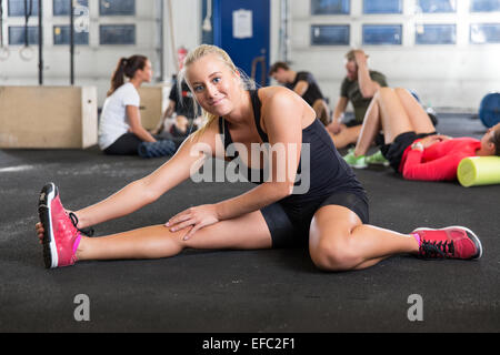 Donna bionda stretching sul pavimento Foto Stock