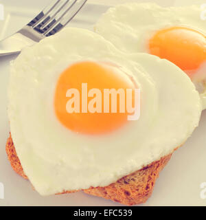 Primo piano di alcuni a forma di cuore le uova fritte servite su pane tostato, con un effetto di filtro Foto Stock