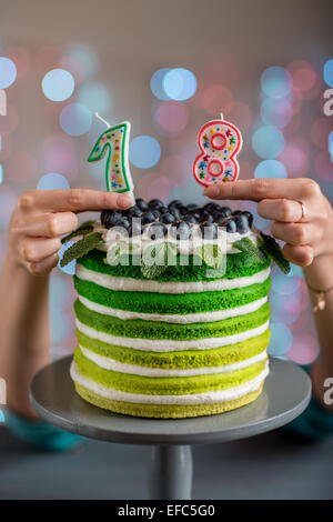 Bella spugna buon compleanno torta con mascarpone e uva sulla torta stand con le candele sulla luce festosa bokeh di fondo Foto Stock