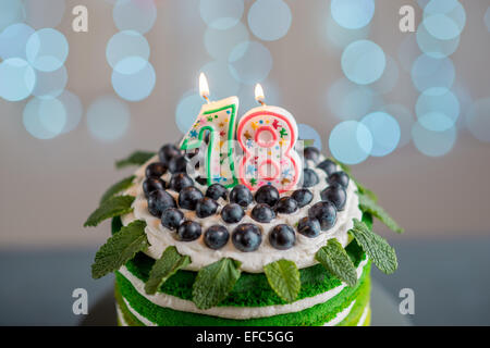 Bella spugna buon compleanno torta con mascarpone e uva sulla torta stand con le candele sulla luce festosa bokeh di fondo Foto Stock