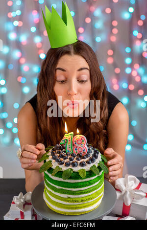 Diciotto ragazza con felice torta di compleanno che soffia su candele sulla festosa sfondo luminoso Foto Stock