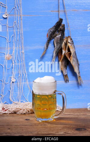 Birra su sfondo blu, essiccato rudd pesce e rete da pesca Foto Stock