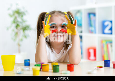 Carino kid ragazza che mostra le sue mani dipinte in colori vivaci Foto Stock