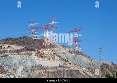 Alta tensione poli di potenza sulla cima di una montagna. Fujairah, Emirati Arabi Uniti Foto Stock