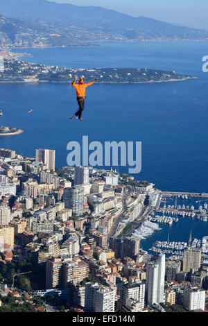 Giovane uomo in rilievo (slacklining) ad un'altitudine di 550 metri sopra il livello del mare. Principato di Monaco in lontananza. La Turbie, Francia. Foto Stock