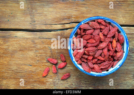 Tibetian essiccati Goji bacche in tazza piccola su vintage tavolo in legno Foto Stock