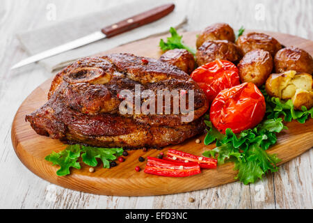 Arrosto di maiale spalla sull'osso con patate Foto Stock