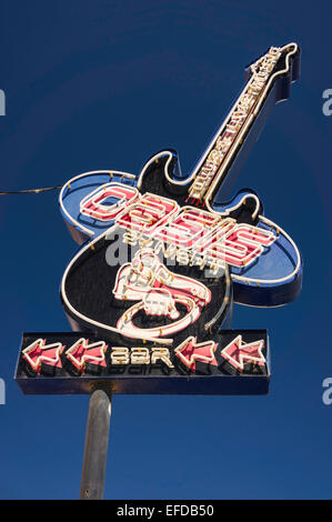 Una scritta al neon a forma di una chitarra elettrica a pubblicizzare l'Oasis Bar in Olhos de Agua, Portogallo. Il cielo è di un blu profondo. Foto Stock