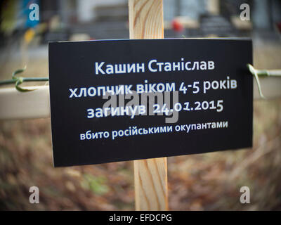 Croci poste dagli attivisti e recanti i nomi di 30 persone che sono morte nel bombardamento in Mariupol su Jan, 24 sono visti iin primo piano una croce con un cartello che dice "Kashin Stanislav boy 4-5 anni, morì 24/01/2015, ucciso da Russo occupanti" vicino all'Ambasciata russa a Kiev, Ucraina, Domenica, 1 febbraio 2015. Foto Stock