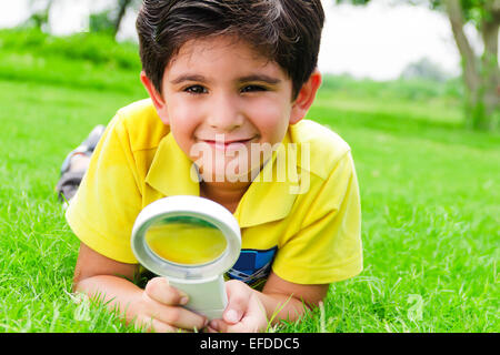 1 bambino indiano boy park lente di ingrandimento ricerca Foto Stock