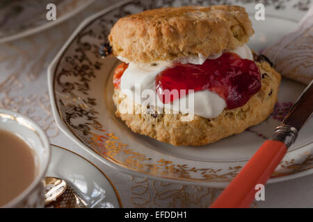 Una tabella per inglese tradizionale tè alla crema. Inceppamento e scones illuminato naturalmente con una tovaglia e belle cina Foto Stock