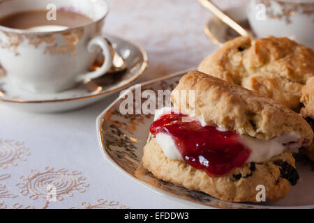 Una tabella per inglese tradizionale tè alla crema. Inceppamento e scones illuminato naturalmente con una tovaglia e belle cina Foto Stock