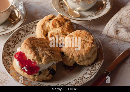 Una tabella per inglese tradizionale tè alla crema. Inceppamento e scones illuminato naturalmente con una tovaglia e belle cina Foto Stock