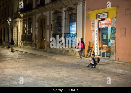 Oaxaca, Messico - una sette-anno-vecchio ragazzo suona la fisarmonica e canta per suggerimenti sulla strada. Foto Stock