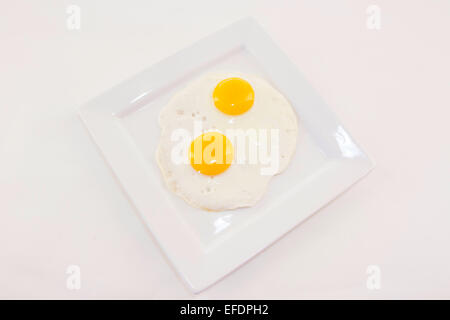 Due uova fritte su una piastra bianca Foto Stock
