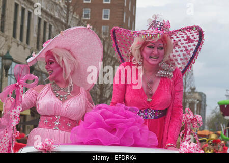 Due frilly costume ladies tutti in rosa con pelle di colore rosa, uno con la barba, ride e wave alle persone durante il Mardi Gras Parade Foto Stock