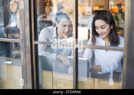 Giovane uomo e donna con tavoletta digitale in cafe Foto Stock