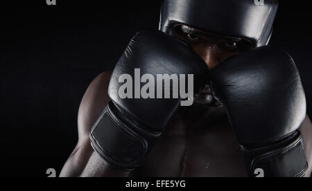 African American boxer indossando indumenti di protezione contro lo sfondo nero. Giovane uomo che esercitano il pugilato. Foto Stock