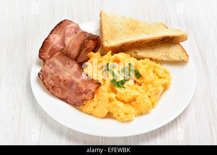 Le uova strapazzate con il bacon e toast sulla piastra bianca, vista ravvicinata Foto Stock