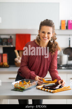 Felice giovane casalinga che serve di zucca al forno Foto Stock