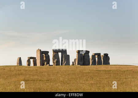 Stonehenge - monumento preistorico nel Wiltshire Inghilterra attraverso il campo di erba marrone, cielo piano Foto Stock