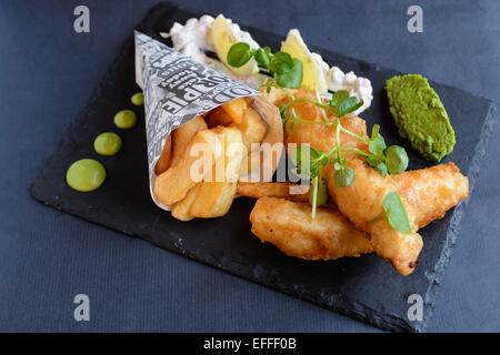 Pesce e patatine, tempura pastella, fiacco pisello, purea di piselli, spicchi di limone e raffinato vernice tartaro Foto Stock