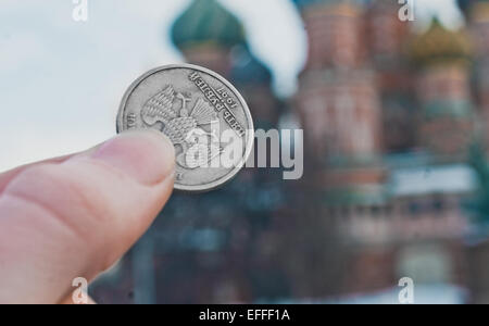 Rublo russo tenutosi sul fondo sfocato di San Basilio cattedrale sulla Piazza Rossa di Mosca, Russia Foto Stock