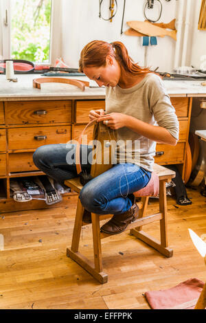 Donna seduta su pony di legatura, cucitura di un tessuto elastico la banda di gomma Foto Stock