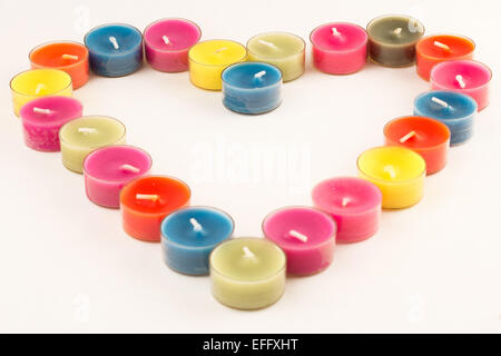 Tealight colorati disposti in una forma di cuore Foto Stock