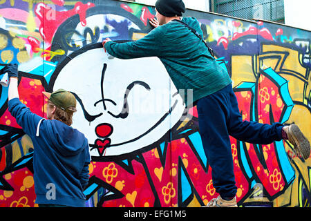 Ragazzi dipinto graffiti sul muro a Lisbona. Foto Stock