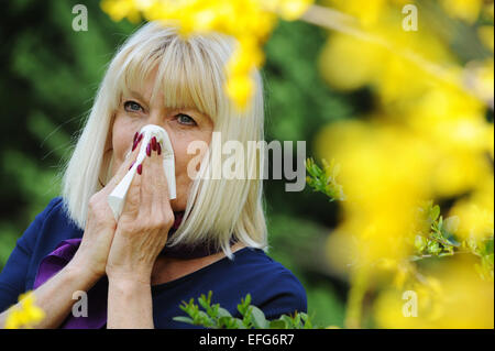 Senior donna soffia il naso per esterno Foto Stock