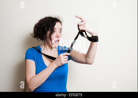 Giovane donna graziosa con il blu t-shirt casual con divertenti espressioni di sorpresa mentre guarda il filmato filmina aspo su backg bianco Foto Stock