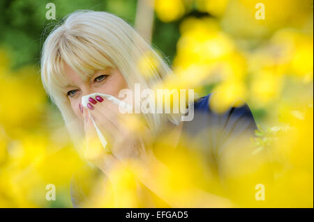 Senior donna soffia il naso per esterno Foto Stock