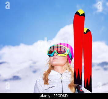 Closeup ritratto di carino sciatore ragazza guardando in alto nel cielo, indossa una speciale maschera sportive, uno stile di vita attivo, godendo di inverno Foto Stock