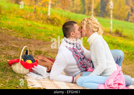 Coppia giovane in amore baciando un picnic su una coperta Foto Stock