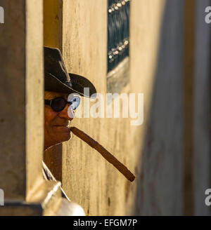 Un cubano anziani seduti su una porta di casa a la luce della sera, fumare un sigaro, Trinidad, Sancti Spiritus Provincia, Cuba Foto Stock