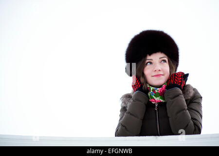 Una femmina vestito in abiti caldi curiosamente guardando con un sorriso Foto Stock