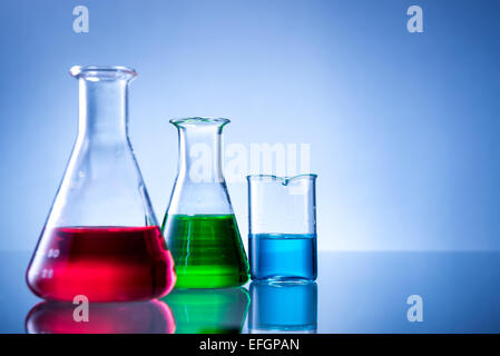 Attrezzature di laboratorio, bottiglie, flaconi con liquido a colori su sfondo blu Foto Stock