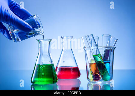 Attrezzature di laboratorio, bottiglie, beute con colore liquido, versata a mano Foto Stock