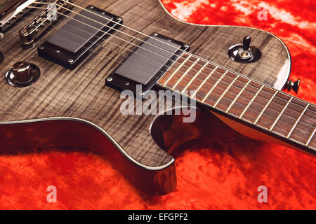 Nero chitarra elettrica sul velluto rosso sfondo Foto Stock