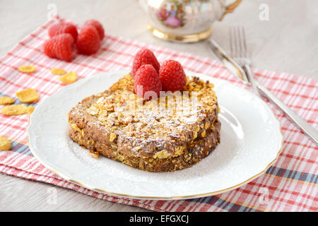 French toast ricoperto con cornflakes, servito con lamponi e zucchero a velo Foto Stock