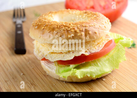 La colazione bagel con la frittata, formaggio, pomodori e lattuga Foto Stock