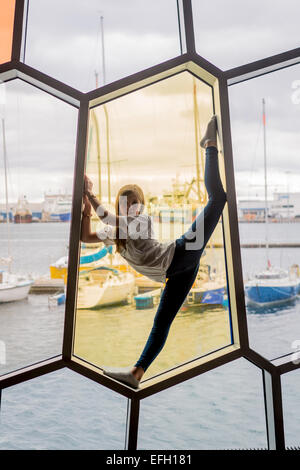 Ragazza giovane stiramento nella finestra al concerto di Harpa e Convention Center, annuale Festival dei Bambini, Reykjavik, Islanda Foto Stock
